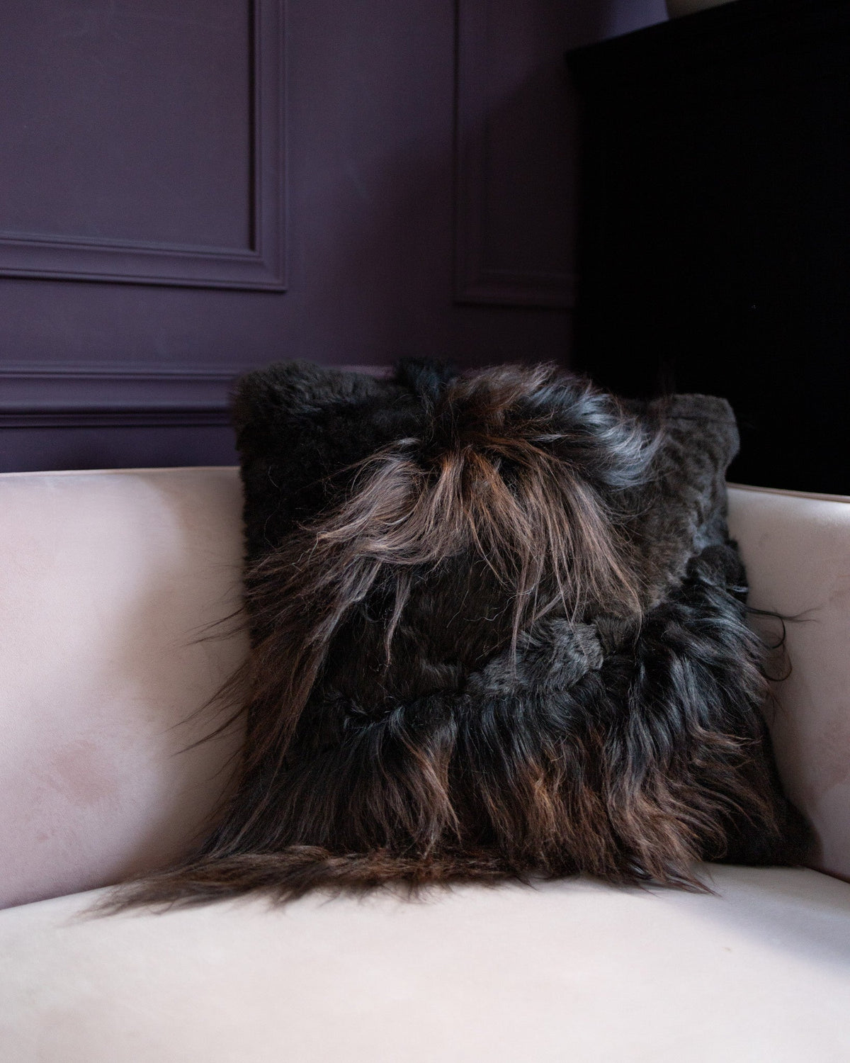 Housse garnie patchwork en peau de mouton brun posée sur un canapé rose poudré