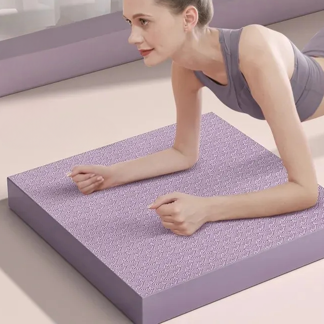 Coussin d'équilibre fitness carré et antidérapant au sol utilisé par une femme