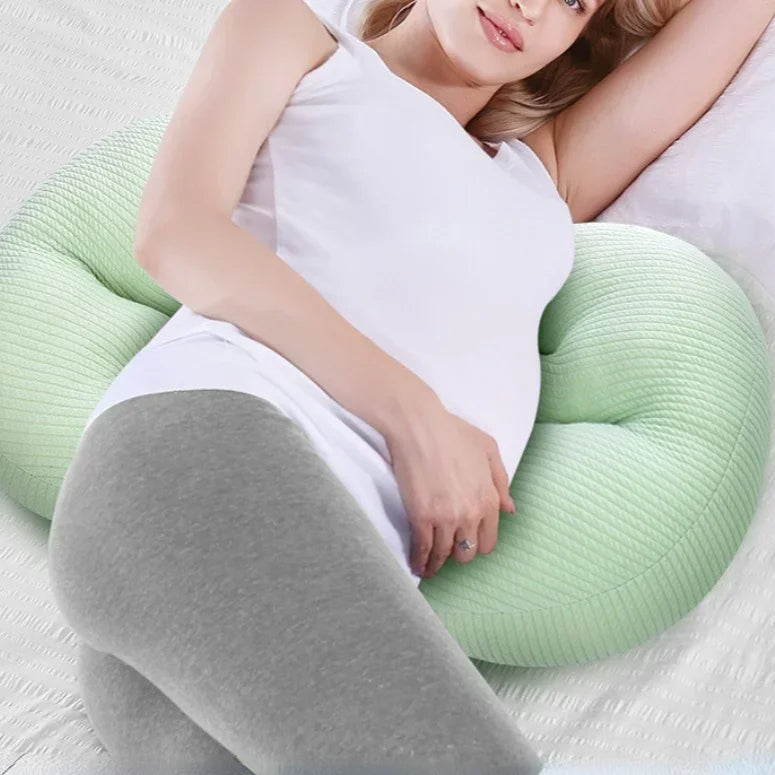 Coussin femme enceinte vert et moelleux sur un lit avec une femme allongée dessus